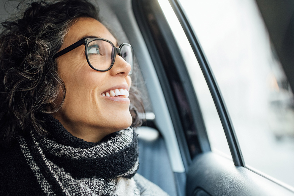 A woman smiling and looking out the window of a car.